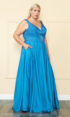 A person with blond hair wears the Embellished Plus-Size Long V-Neck Prom Dress W1110—a sleeveless blue gown with pockets—while standing on a wooden floor against a beige wall.