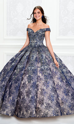 A young woman smiles against a white ornate background wearing the Princesa Lace Ball Gown Quinceañera Dress PR11921, an off-the-shoulder, floor-length gown with intricate blue and silver lace detailing.