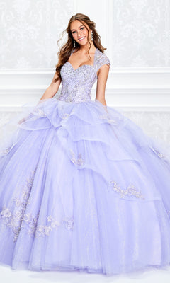 A young woman smiles at the camera in front of a white ornate wall, wearing the Princesa Beaded Lace Quinceañera Dress PR11923, a sparkling lavender ball gown adorned with stunning beaded lace.