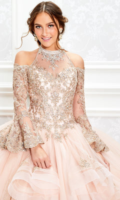 Young woman in the Princesa Halter Ball Gown Quinceañera Dress PR11927 with gold embroidery and sheer sleeves stands against a white, patterned background.