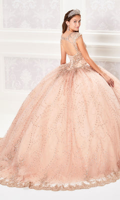 A woman in the Princesa PR21964 Cap-Sleeve Quinceanera Dress—sparkling, peach-colored with a full skirt and lace applique—stands elegantly in a room, facing away and glancing over her shoulder.