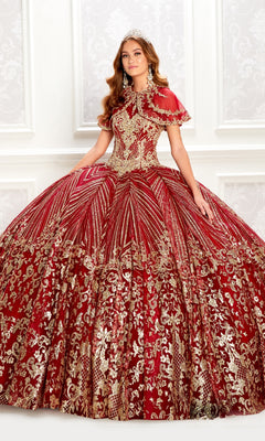 A woman models the Princesa PR22034, a wine red quinceanera dress with gold embellishments, full skirt, and a removable bolero jacket, standing indoors against an ornate white wall.