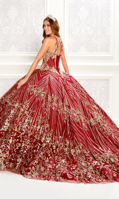 A woman models the Princesa PR22034 wine red quinceanera dress with gold embellishments and intricate patterns, posing in an ornate white room.