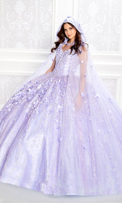 A woman wears the Flower Quince Dress: Princesa by Ariana Vara PR22036—a light purple gown with floral details, matching cape, and hood—while standing before a white patterned wall.