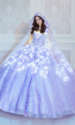 A woman stands in a white room wearing the Princesa by Ariana Vara PR22036 Flower Quince Dress, a lavender ball gown with a matching hooded cape illuminated by small white lights for a magical glow-in-the-dark effect.