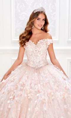 A young woman poses in a white, ornate room wearing the Flower Quince Dress: Princesa by Ariana Vara PR22036, an off-the-shoulder embellished pink ball gown, paired with a silver tiara.