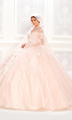 A woman in the Flower Quince Dress (Princesa by Ariana Vara PR22036), a light pink embellished ball gown with matching cape and headscarf, stands before a white ornate background.