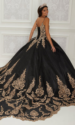A woman stands in an elegant room, looking over her shoulder in the Quinceanera Dress PR22141 By Princesa—a black ball gown with gold embroidery, a corset back, and a matching headpiece.
