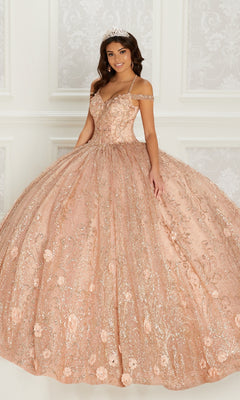 A woman stands in an ornate room with white decorative walls, wearing the sparkling Quinceanera Dress PR22144 by Princesa in peach glitter with detachable straps and a tiara.