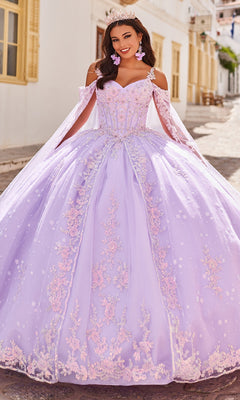 A woman stands outdoors wearing the Quinceanera Dress PR30087 By Princesa, featuring a lavender hue, corset bodice, pink embroidery, off-shoulder sleeves, a tiara, and pink floral earrings.