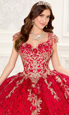 A woman in the Quinceanera Dress PR30088 By Princesa, featuring red and gold lace embroidery, stands with a tiara, earrings, and necklace against a decorative white background.