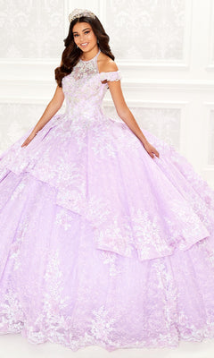 A woman wears the Quinceanera Dress PR30089 By Princesa, featuring embroidered lace details and a voluminous lavender design, standing indoors against a white ornate background.