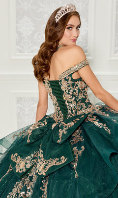 A woman wearing the Quinceanera Dress PR30112 By Princesa, featuring an off-the-shoulder neckline in emerald green with gold embroidery and a jeweled tiara, sits and looks over her shoulder.