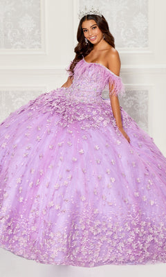 A woman wearing a silver tiara and the Princesa Quinceanera Dress PR30115, an off-the-shoulder lavender gown with floral appliqués, stands smiling before a decorative white wall.