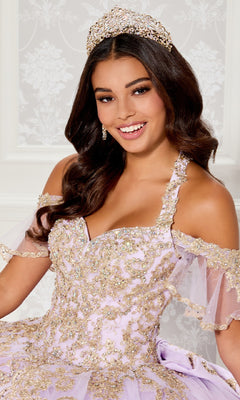 A woman with long wavy hair smiles at the camera, wearing a jeweled tiara and the ornate PR30118 Quinceanera Dress by Princesa—an off-the-shoulder lilac gown featuring gold embellishments and glitter embroidery.
