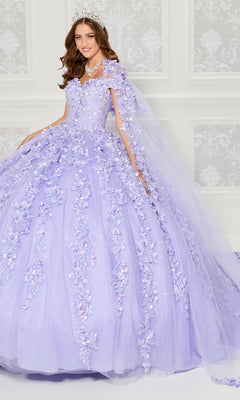 A woman in the Princesa PR30120 lavender floral tulle quinceanera dress with 3D appliqués, tiara, and necklace stands before an ornate white wall.