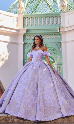 A young woman smiles as she poses before a mint green domed structure, her hands resting gracefully on the ornate lilac Quinceanera Dress PR30134 By Princesa, featuring a strapless corset bodice and voluminous ball gown skirt.