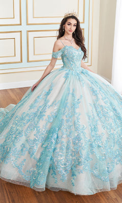A woman in the Lace Embroidered Quinceanera Dress: Princesa PR30153, a light blue off-the-shoulder gown with a lace corset bodice and tiara, stands indoors on a wooden floor.