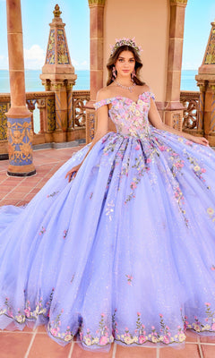 A woman in the Quinceanera Dress PR30155 By Princesa, a large off-the-shoulder lavender gown with 3D floral embroidery, stands on a terrace overlooking the ocean.