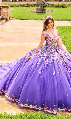 A woman poses outdoors on a walkway beside a lawn, wearing the Quinceanera Dress PR30155 By Princesa in purple glitter with 3D floral embroidery and a matching headpiece.