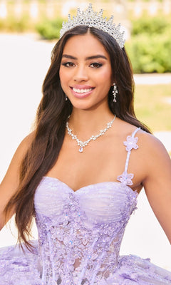 A young woman wearing a jeweled tiara and the Quinceanera Dress PR30158 By Princesa, featuring lavender floral embellishments and embroidered lace, smiles at the camera outdoors.
