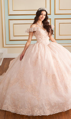 A young woman stands in an ornate room with decorative wall paneling, wearing the Quinceanera Dress PR30163 By Princesa—a voluminous, light pink gown with off-the-shoulder sleeves and a sparkling tiara.
