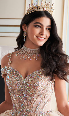 A woman smiles and looks slightly to the side, wearing the Quinceanera Dress PR30173 By Princesa with a jeweled crown, ornate choker, and drop earrings, set against an elegant indoor background.