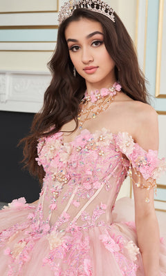 A young woman wears the Quinceanera Dress PR30178 By Princesa, featuring a jeweled tiara, off-shoulder pink floral design, corset bodice, intricate embroidery, and beadwork as she stands indoors.