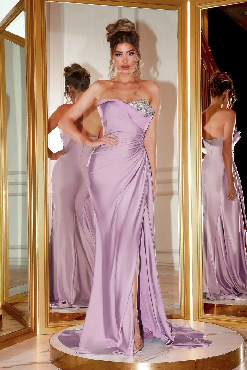 A woman wears the Long Formal Dress PS21218 by Portia and Scarlett in mauve, featuring a strapless design, thigh-high slit, and silver embellishments, as she stands before mirrored panels.