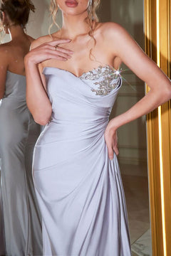 A woman stands gracefully in front of a mirror wearing the Long Formal Dress PS21218 by Portia and Scarlett, a light lavender strapless gown with an embellished, sparkling jeweled bodice.