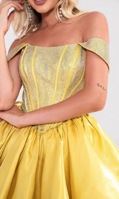 A woman wears the Portia and Scarlett PS24762 short homecoming dress, which features an off-shoulder yellow satin skirt and a glittery rhinestone corset bodice. Only her torso and part of her face are shown.