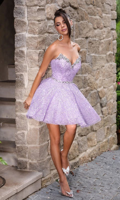 A woman stands against a stone wall in the Portia and Scarlett PS24765, a strapless sparkly lavender fit-and-flare mini homecoming dress with crystal embellishments, one leg crossed and head tilted.