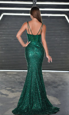 A woman stands with her back to the camera in an industrial setting, wearing the sparkling green Long Prom Dress PS24943 by Portia and Scarlett, featuring floor-length sequins, double shoulder straps, and a fitted silhouette.