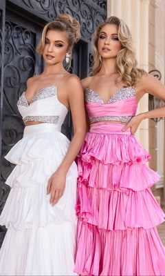Two women stand side by side in Portia and Scarlett PS25164 long prom dresses with sparkling bodices—one white, one pink—as they pose gracefully before an ornate doorway.