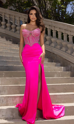 A woman stands on stone steps wearing the Portia and Scarlett PS25187 long formal dress in hot pink, featuring a strapless beaded bodice, thigh-high slit, and silk skirt with lush greenery and a balustrade behind her.