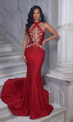 A woman poses for a formal photo on marble steps, wearing the red Portia and Scarlett PS25206 long formal dress with a fitted mermaid silhouette and silver embellishments, one arm resting on a column.