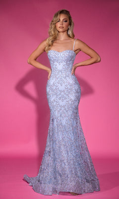 A woman stands against a pink background wearing the Portia and Scarlett PS25251 long prom dress, featuring light purple glitter lace, thin straps, a corset bodice, and a flared mermaid skirt.