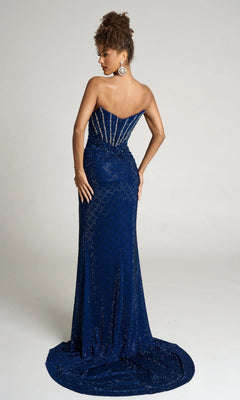 A woman models the Portia and Scarlett PS26016, a strapless, floor-length navy blue beaded gown with sparkling details, posing with her back to the camera against a plain background.