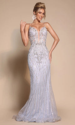 A woman wearing the Portia and Scarlett PS26033 long formal dress, featuring a fitted silhouette, thin straps, intricate beadwork, and a sheer bodice, stands against a plain beige background.