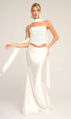 A woman models the Portia and Scarlett PS26042 long formal dress in white, featuring a strapless beaded corset top and matching satin skirt, posing against a plain light background.