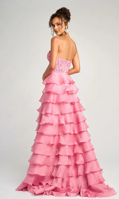 A woman models the Long Formal Dress: Portia and Scarlett PS26048, a strapless, floor-length pink ruffled gown with an embroidered corset bodice, standing against a plain light background and looking over her shoulder.