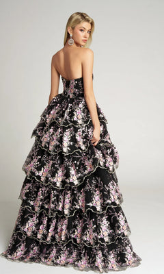 A woman in the Portia and Scarlett PS26051 Strapless Floral Ball Gown, featuring pink and white embroidered floral appliqué, stands facing away while looking over her shoulder.