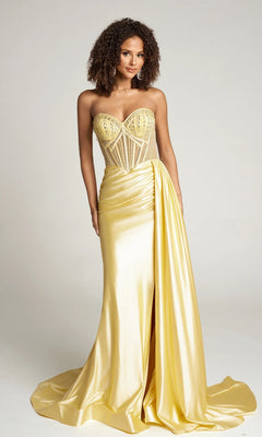 A woman wears the Portia and Scarlett PS26056 long formal dress in yellow, featuring a strapless design with a sheer corset bodice and a draped, ruched skirt highlighted by a front slit.