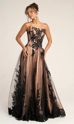 A woman wears the Portia and Scarlett PS26061 long formal dress in black/nude, featuring an a-line silhouette, strapless corset bodice, floral lace overlay, nude underlayer, and a full glitter tulle skirt.