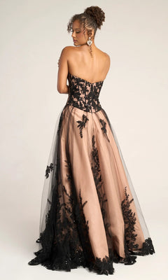 A woman stands with her back to the camera in the Portia and Scarlett PS26061 long formal dress, showcasing its strapless corset bodice, nude underlayer, and black lace overlay against a plain background.