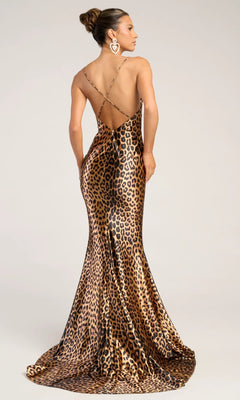 A woman models the Portia and Scarlett PS26257 long prom dress, featuring a form-fitting leopard print, thin crisscross straps, a backless floor-length design, and poses facing away from the camera.