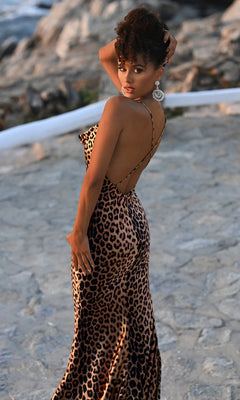 A woman poses outdoors on a stone pathway, looking over her shoulder at the camera while wearing the Portia and Scarlett PS26257 long prom dress.