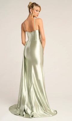 A woman stands with her back to the camera in the Portia and Scarlett PS26270 long prom dress, featuring light green satin, thin straps, a low back, and a sheer corset bodice against a plain background.