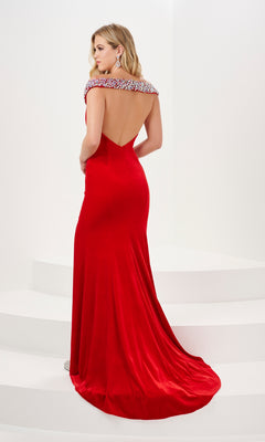 A woman stands on white steps, facing away in the Long Prom Dress 14195 by Panoply—a floor-length red stretch velvet gown with an open back and jeweled neckline.