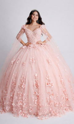 A woman poses against a plain background in the Nina Canacci Q100 long quinceanera dress, a voluminous light pink ball gown with floral appliqués, sheer sleeves, and a tiara.